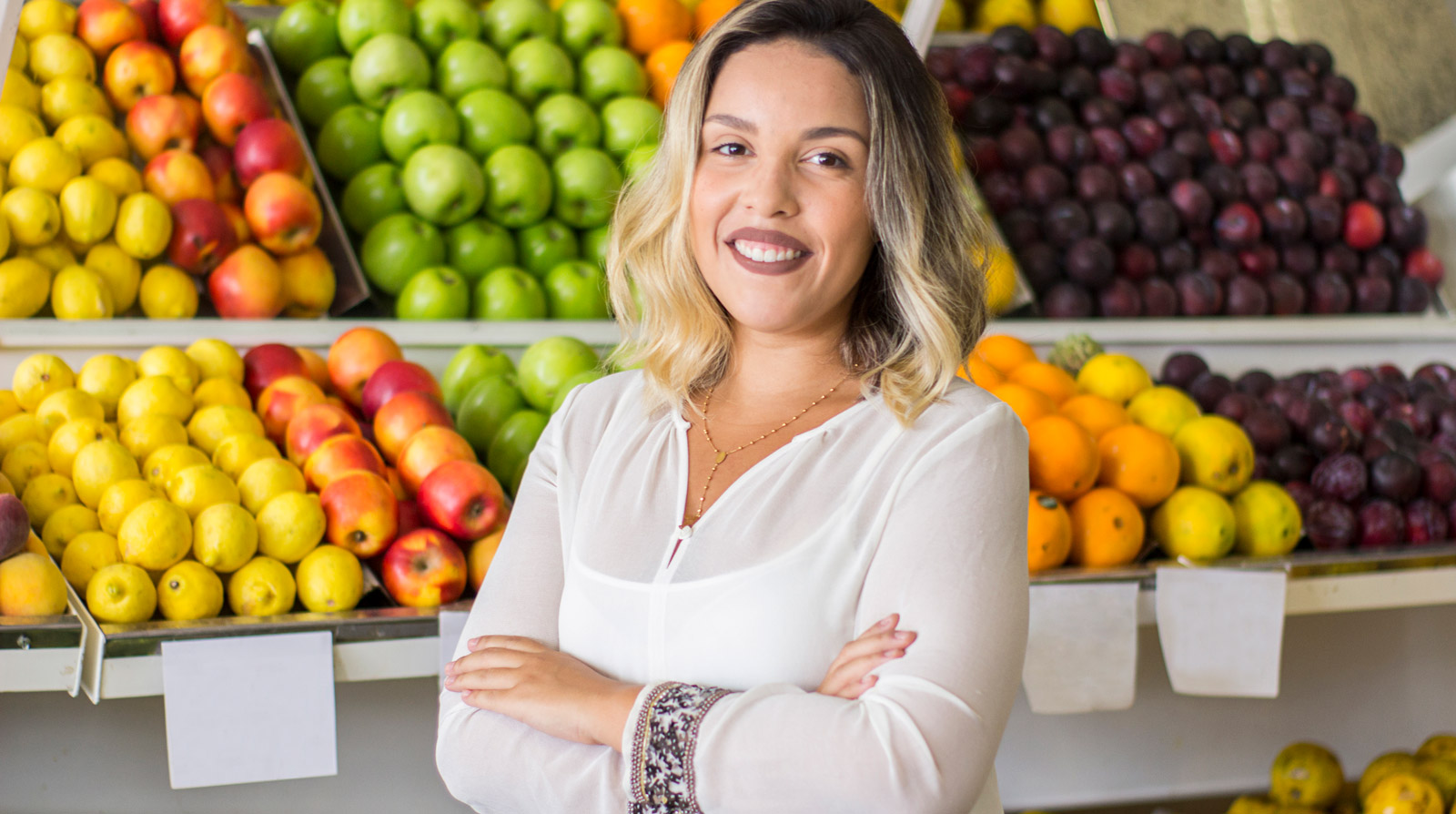 A woman standing in front of fresh fruits and vegetables in a grocery store.